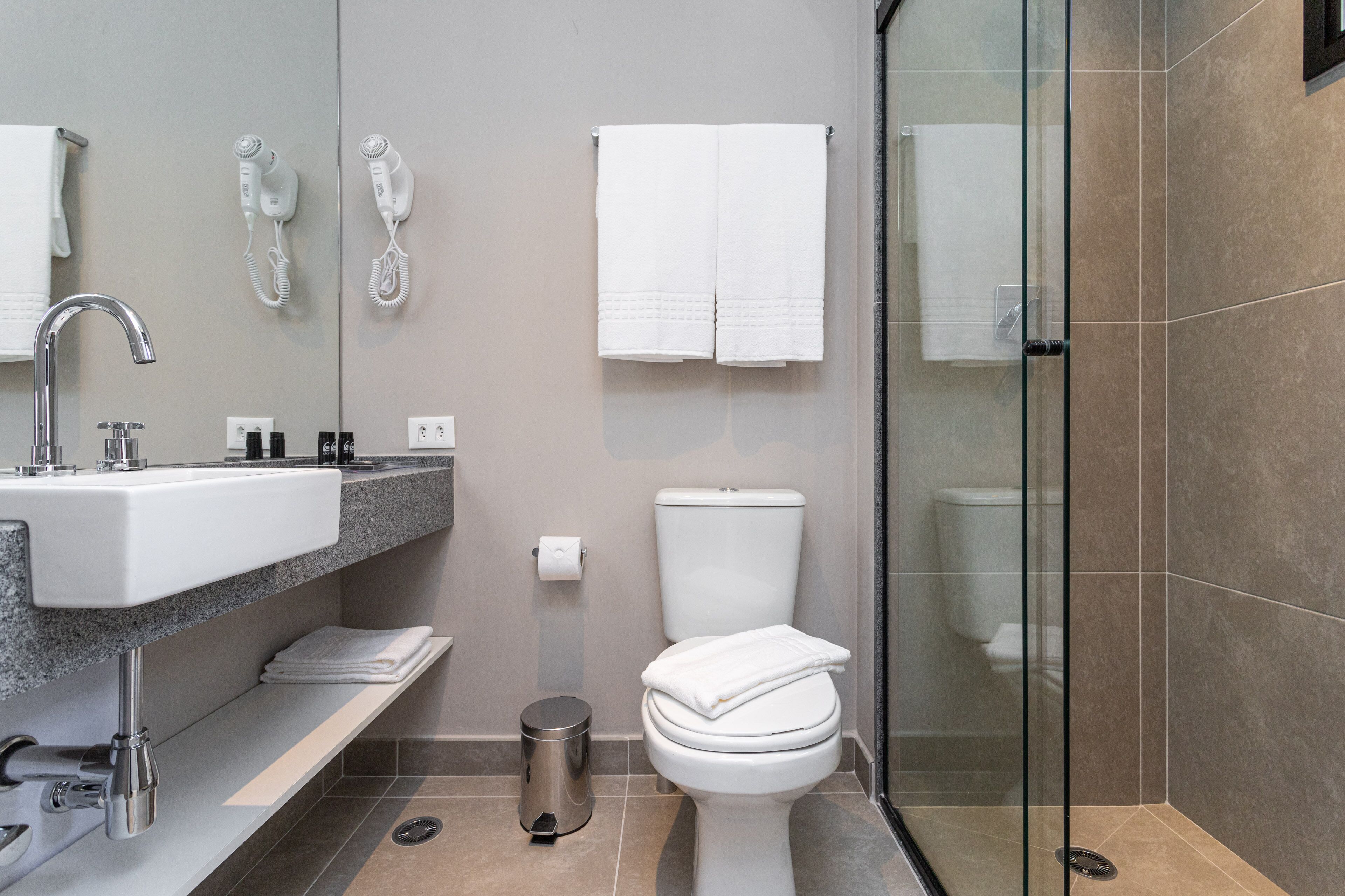 A modern bathroom with a sink, mirror, toilet, and shower.