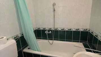 Et badeværelse med badekar, toilet og vask.