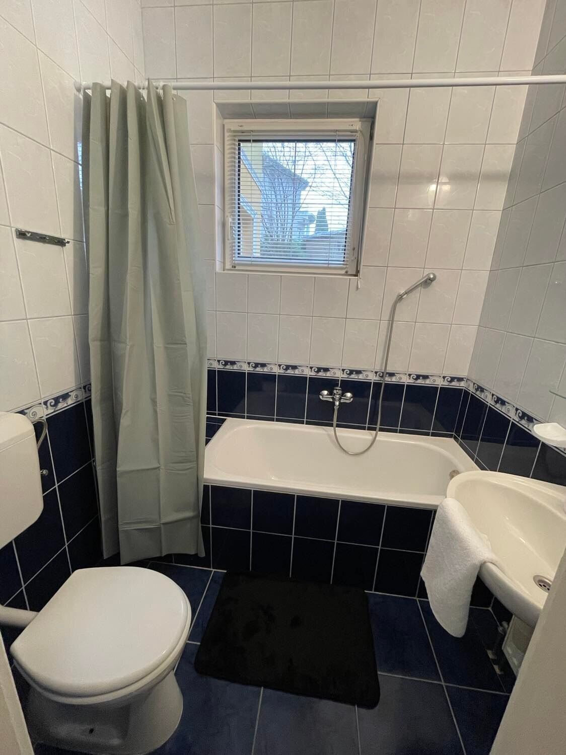 Un baño con bañera, inodoro y ventana.