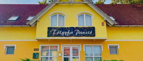 Un bâtiment jaune sur lequel on peut lire l’inscription « Tölgyúbánzi Panzió ».