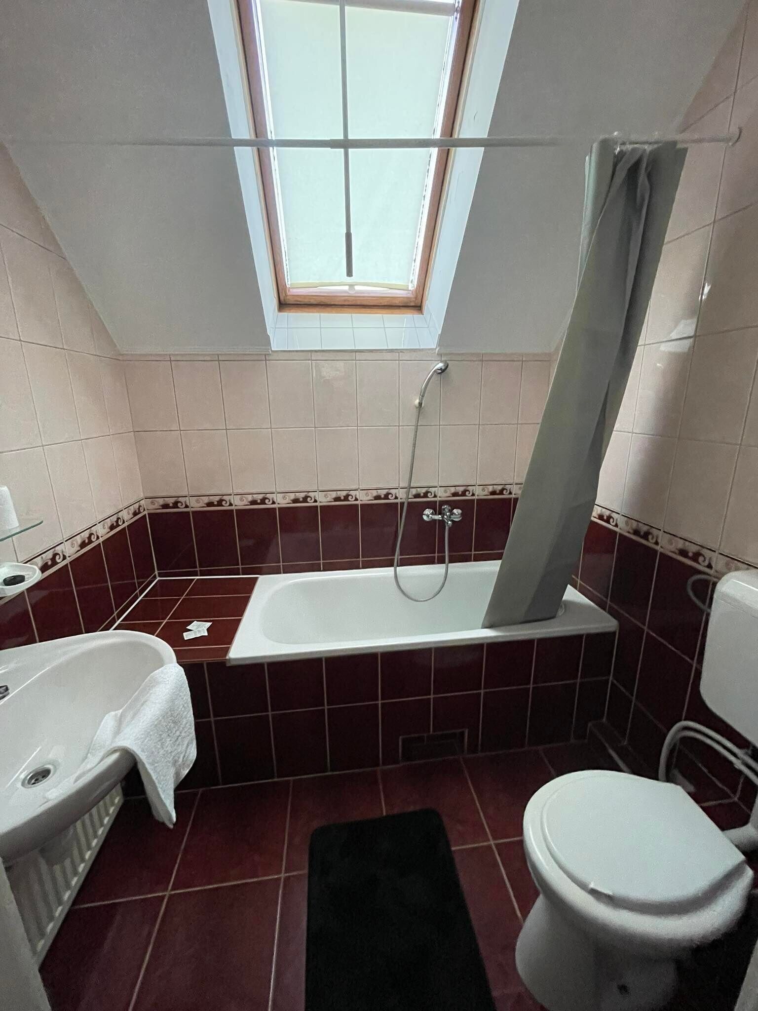 Une salle de bain avec une baignoire, des toilettes et une fenêtre située au-dessus de la baignoire.