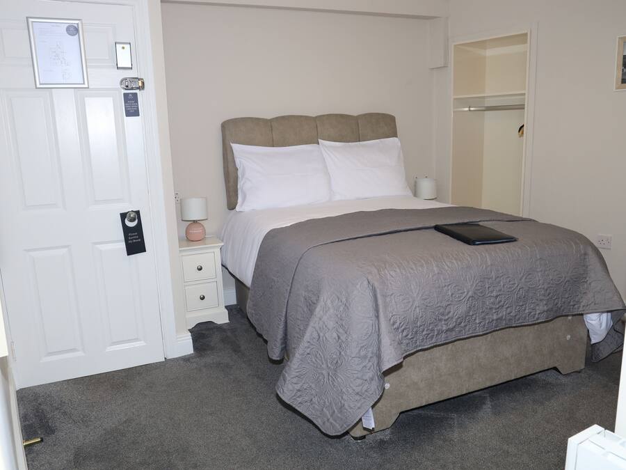 Un dormitorio con cama, mesita de noche, armario y puerta.