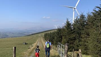 Ein Weg, der bergauf führt, mit einer Windkraftanlage im Hintergrund.