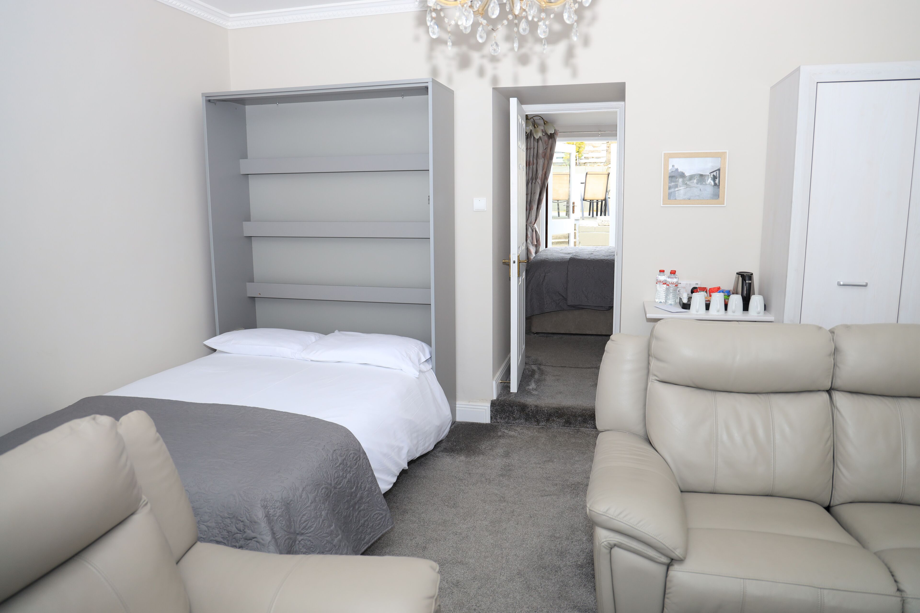 Una habitación de hotel con cama, sofá, armario y una mesita con artículos de aseo.