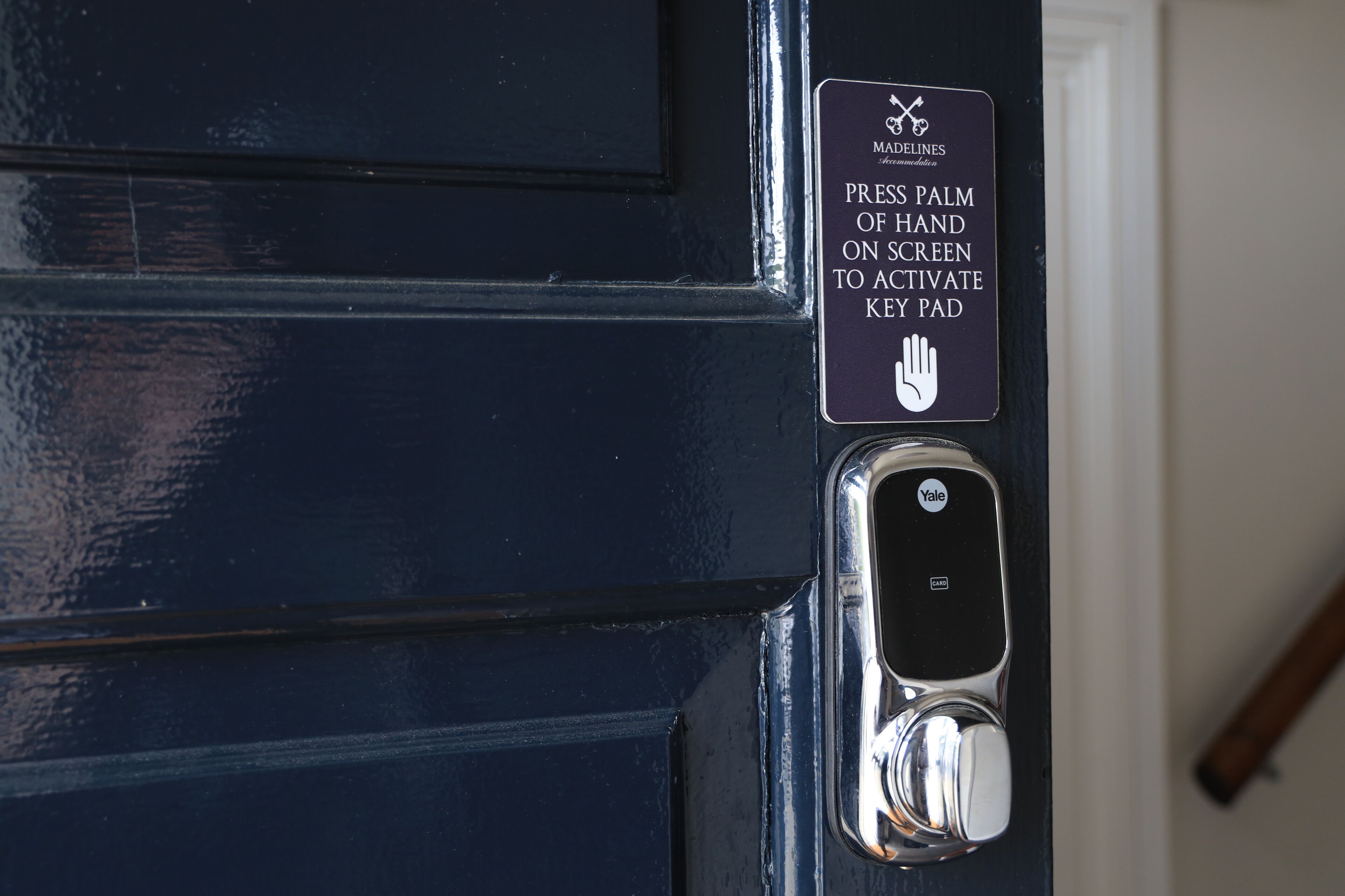 A door with a Yale lock and a sign instructing to press palm of hand on screen to activate key pad.