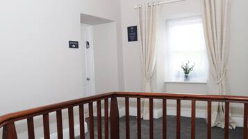 A staircase with a wooden handrail leading to a room. A sign indicates "ROOM 8" and another sign with a message about the room's features.