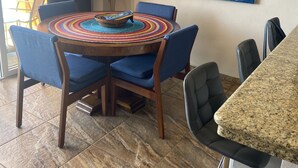 Un coin repas avec une table ronde, des chaises bleues et un set de table coloré en fibres tressées.