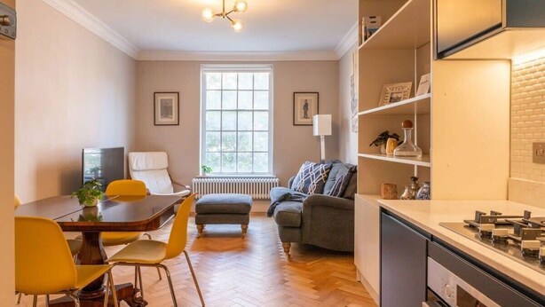 A modern kitchen with a dining area, a sofa, and a radiator. - 2-bed Flat Near Marylebone High Street · Sleeps 4 (London)