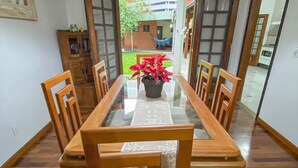 A dining area with a glass-top table, wooden chairs, and a potted plant. - Casa com espaço gourmet, home office e 3 suítes \- Granja Viana (Carapicuiba)