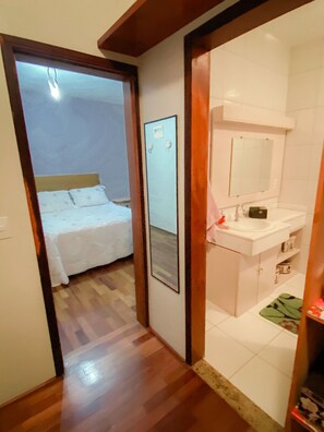A bedroom with a bed and a bathroom with a sink and mirror. - Casa com espaço gourmet, home office e 3 suítes \- Granja Viana (Carapicuiba)