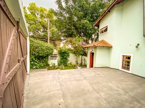 Stroll through this serene courtyard surrounded by lush greenery and a low wall, featuring a convenient entrance to the adjacent building.