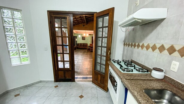 A kitchen with a gas stove, sink, and a window with a view of the outside. - Casa com espaço gourmet, home office e 3 suítes \- Granja Viana (Carapicuiba)
