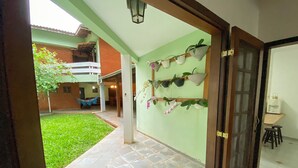 A courtyard with a tiled floor, a hammock, and potted plants on the walls. - Casa com espaço gourmet, home office e 3 suítes \- Granja Viana (Carapicuiba)