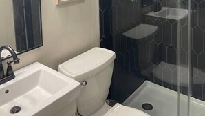 Une salle de bain moderne avec deux lavabos, des toilettes et une douche à parois de verre.