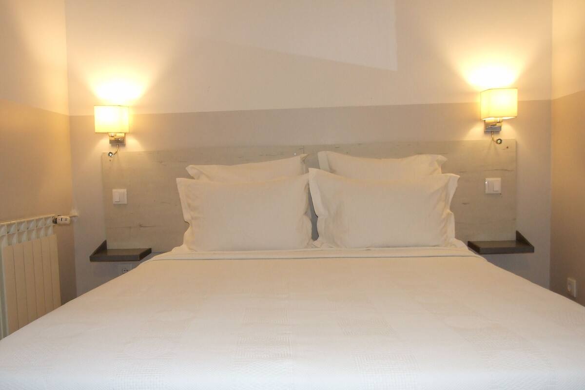 Una cama bien hecha con sábanas blancas en una habitación de hotel.