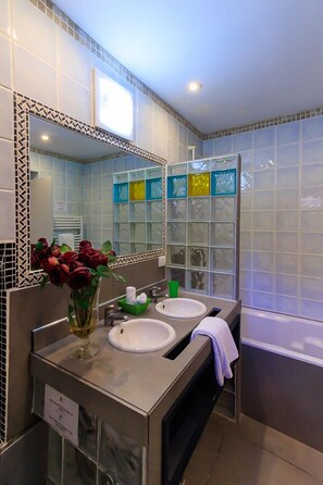Un baño moderno con dos lavamanos, un espejo grande y una cabina de ducha con mampara de cristal.