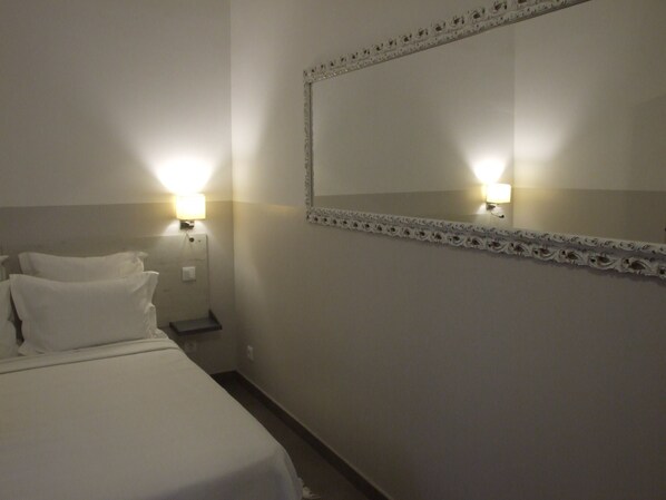 A hotel room with a bed, two wall-mounted lights, and a decorative mirror with a floral frame. - Quinta dos Amigos (Loulé)