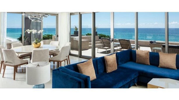 Ein modernes Wohnzimmer mit einem blauen Sofa, weißen Sesseln und einem Esstisch.