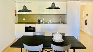Una cocina compacta con una mesa y sillas, horno empotrado e iluminación colgante.