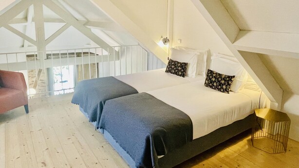 Un dormitorio con una cama grande, una silla y suelo de madera.