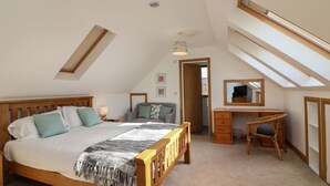 Une chambre avec un plafond en pente, un lit en bois, un bureau et une chaise.
