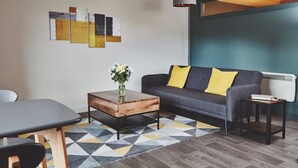 Un salon moderne avec un canapé, une table basse et des œuvres d’art accrochées au mur.