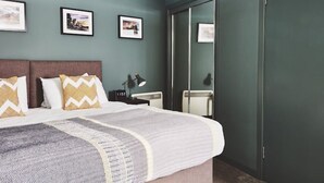 Une chambre à coucher moderne, avec un lit, des tables de chevet, une lampe et des tableaux encadrés accrochés au mur.