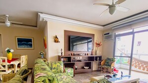 A living room with a large sofa, a TV, and a ceiling fan.
