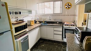 A kitchen with white cabinets, a microwave, an oven, a toaster, and a fan.