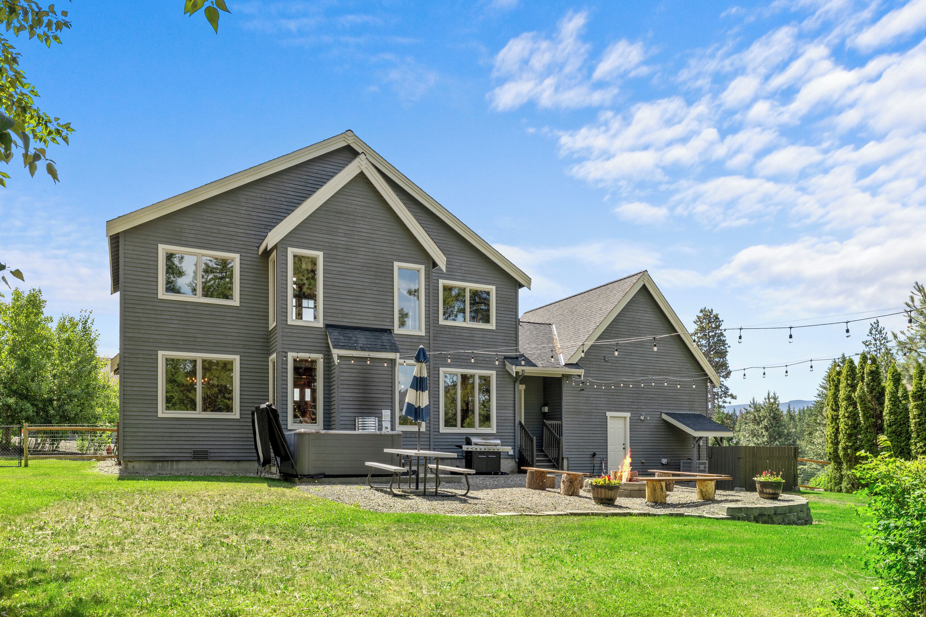 A two-story house with a patio area, a barbecue grill, and a covered seating area.