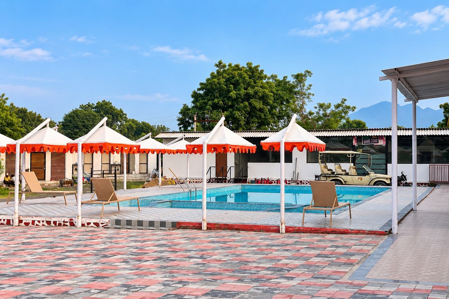 Un espace piscine équipé de parasols, de chaises longues et d’un véhicule tout-terrain.