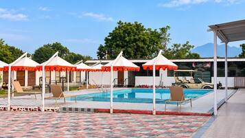 Un espace piscine équipé de parasols, de chaises longues et d’un véhicule tout-terrain.