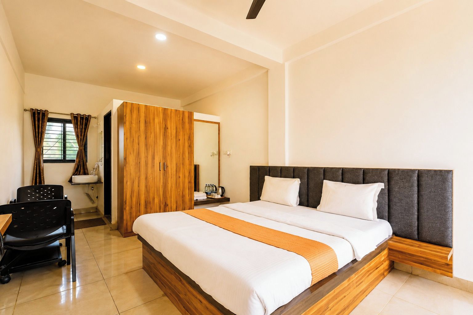 Une chambre d’hôtel avec un lit, un bureau, une chaise et une armoire.