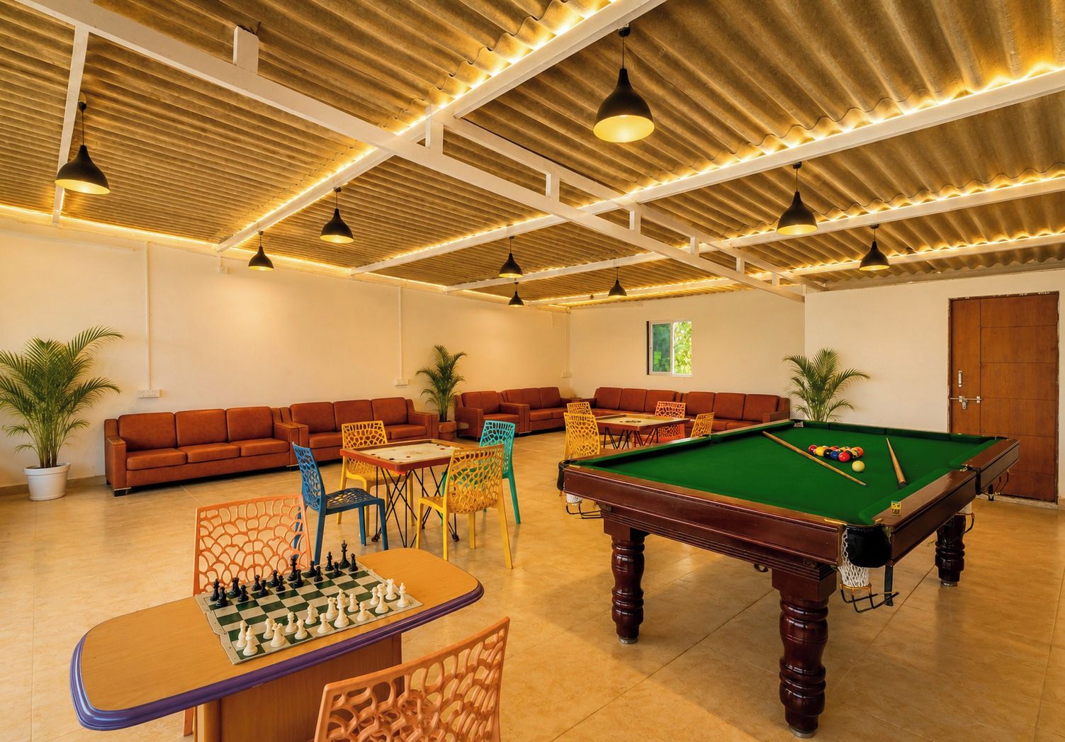Une salle de billard équipée d’une table de billard, d’une table d’échecs et de plusieurs canapés.