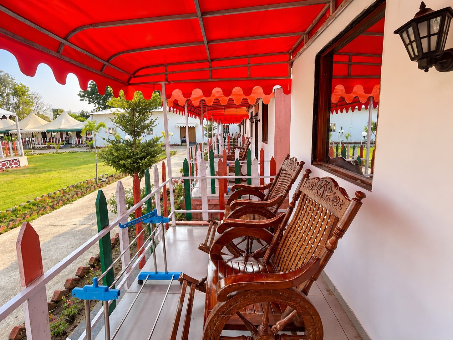 A covered outdoor seating area with wooden chairs and a blue scooter.