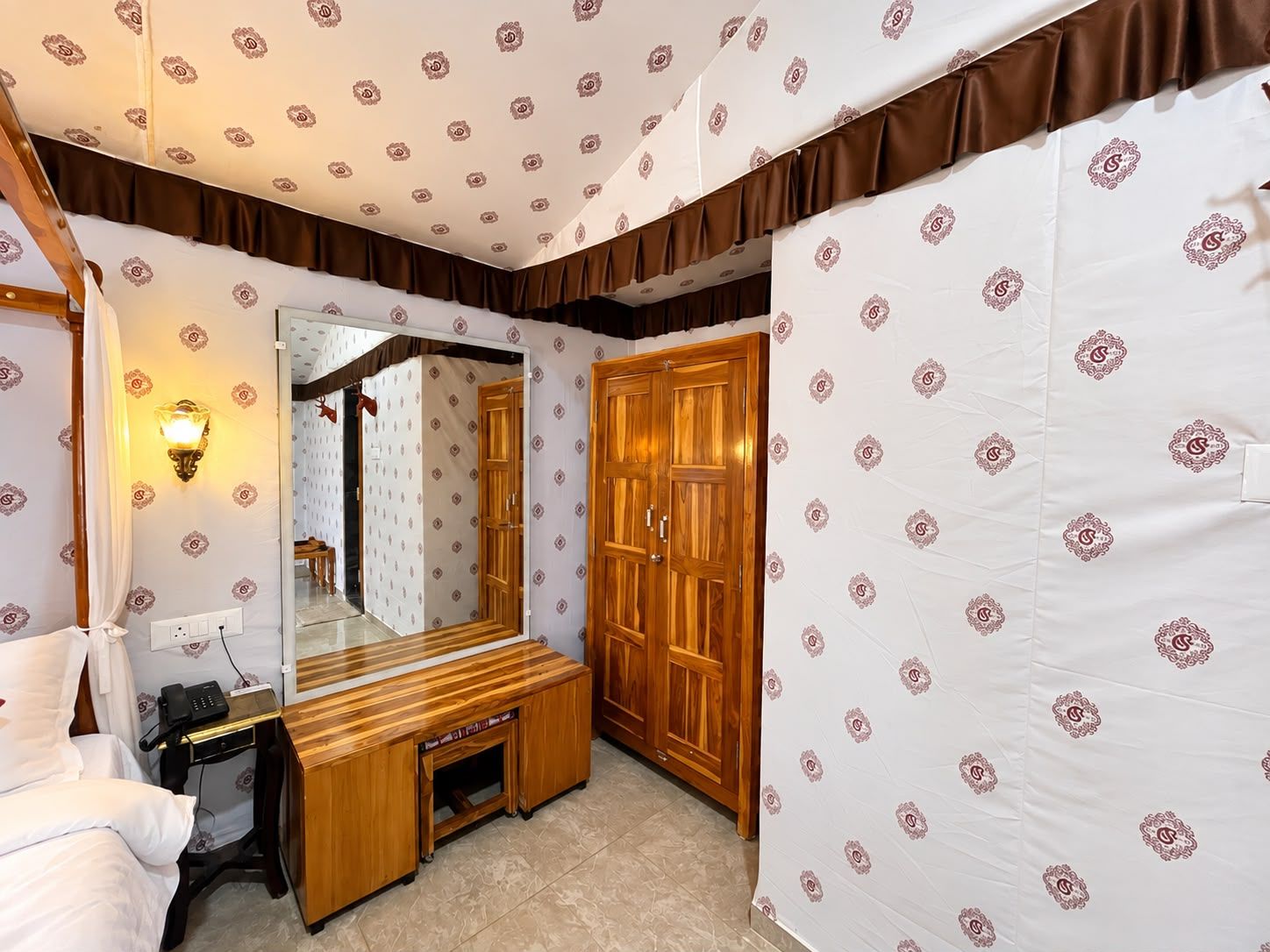 Una habitación de hotel con cama, mesita de noche, lámpara, armario y espejo.