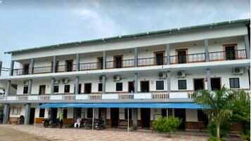 A multi-story hotel with a flat roof, balconies, and a covered outdoor area with a blue awning.