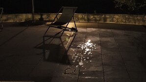 An outdoor patio area with a single lounge chair and a large umbrella, under a night sky with a visible moon. - The Dovecote (REILHAGUET)