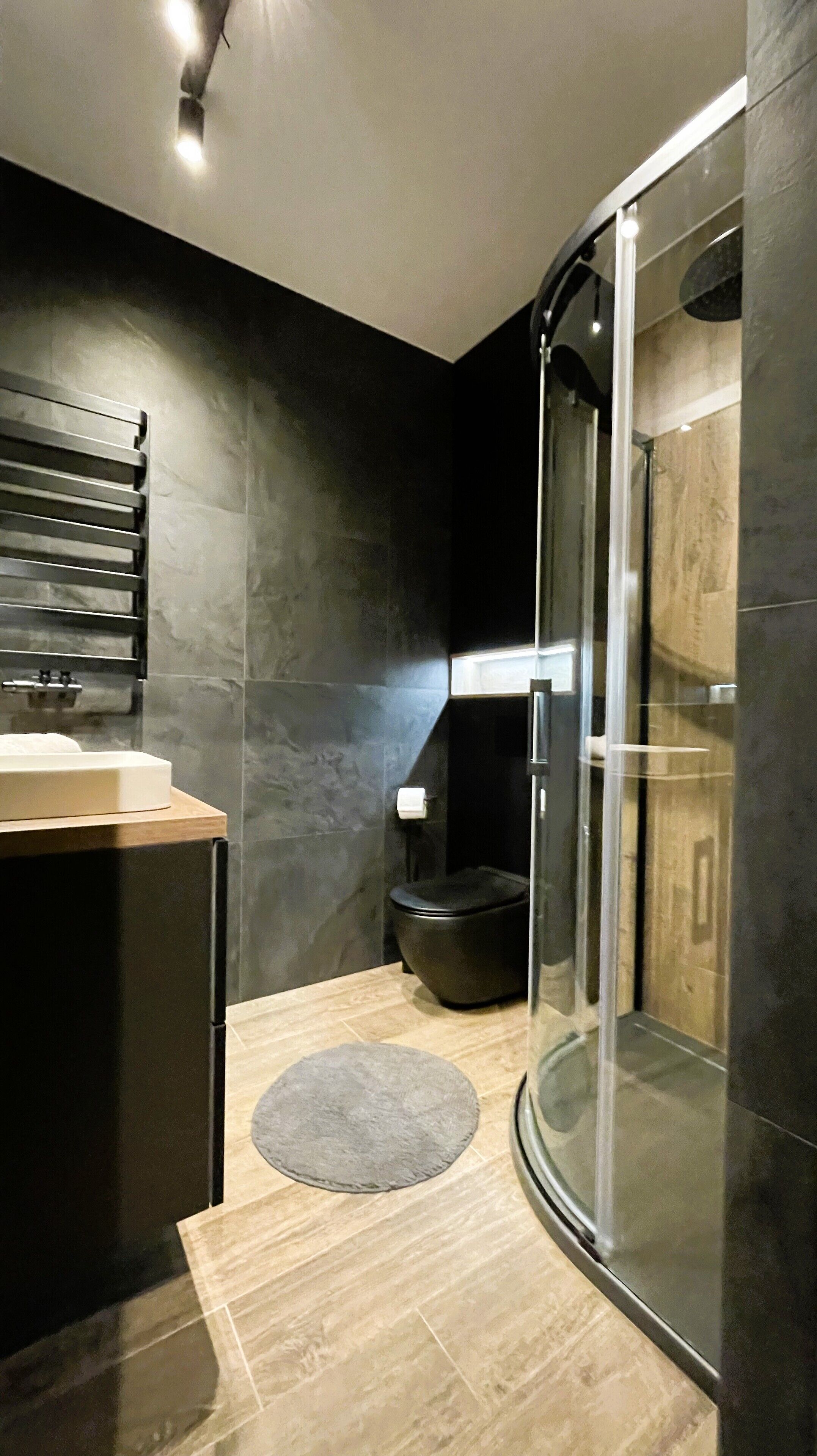 A modern bathroom with a glass shower enclosure, a toilet, and a sink area.