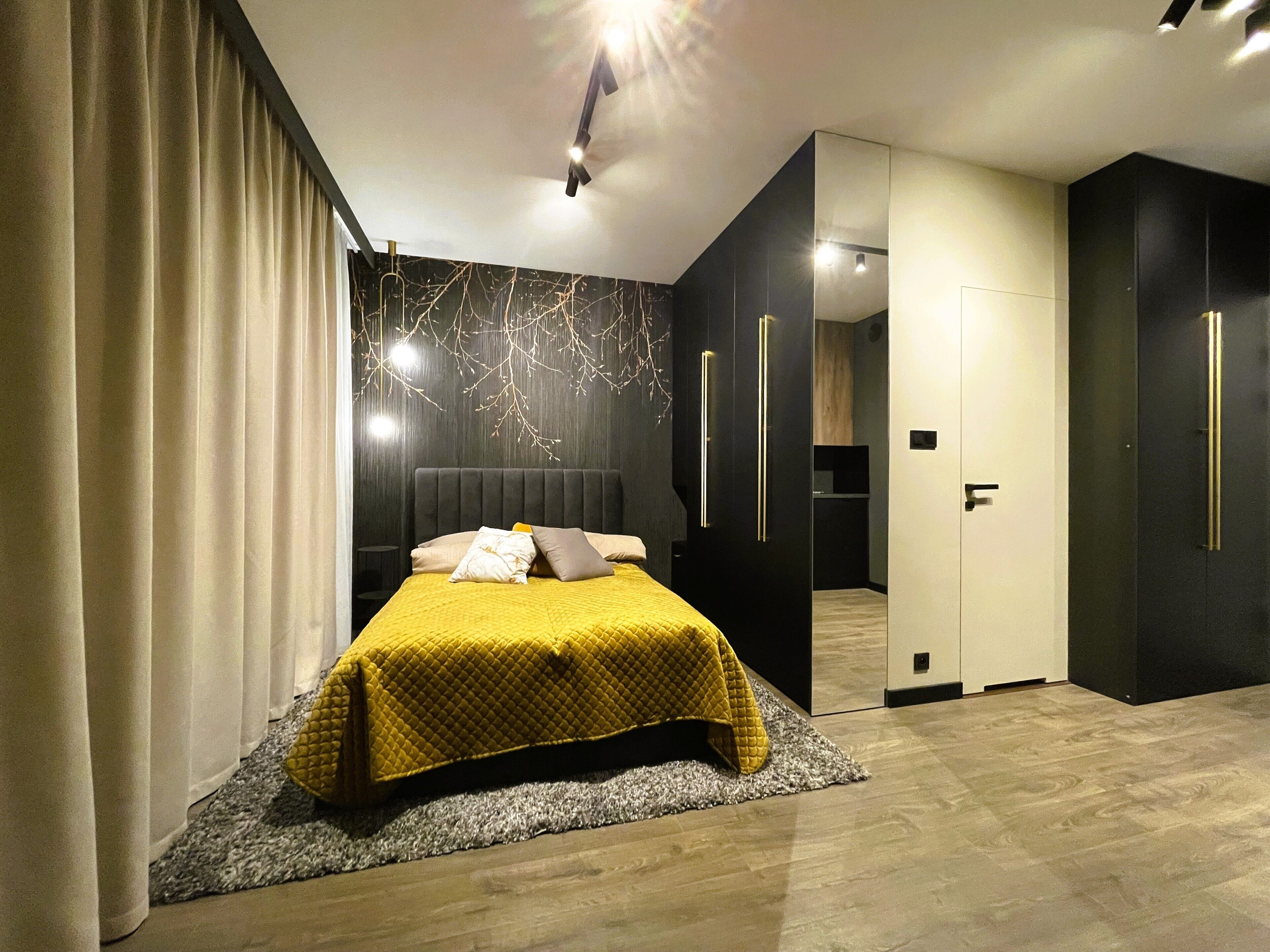 Ein modernes Schlafzimmer mit einem großen Bett, dunklen Wänden und einem sichtbaren Badezimmer.