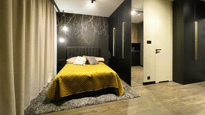 Camera da letto moderna con un letto grande, pareti scure e bagno in vista.