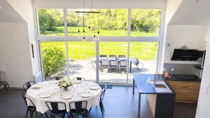 Una cucina moderna con una grande finestra, un'area pranzo con tavolo apparecchiato per quattro persone e vista su un giardino.