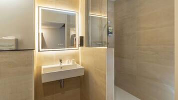 Een moderne badkamer met een douchecabine van glas, een wit wastafelmeubel met een spiegel erboven en behangplaten in beige tinten.