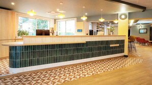 A reception area with a counter, seating, and a patterned floor. - Sure Hotel by Best Western Caen Memorial (Caen)