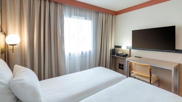 A hotel room with two beds, a desk, a television, and a window with curtains. - Sure Hotel by Best Western Caen Memorial (Caen)