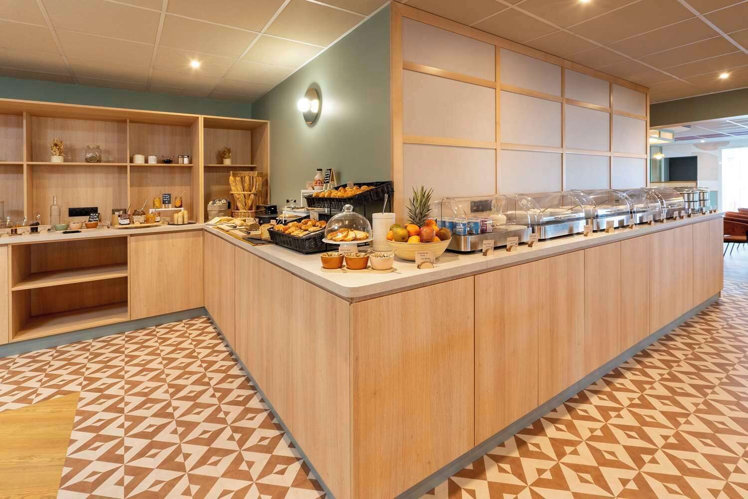 Un buffet pour le petit-déjeuner proposant divers aliments et un saladier rempli de fruits.