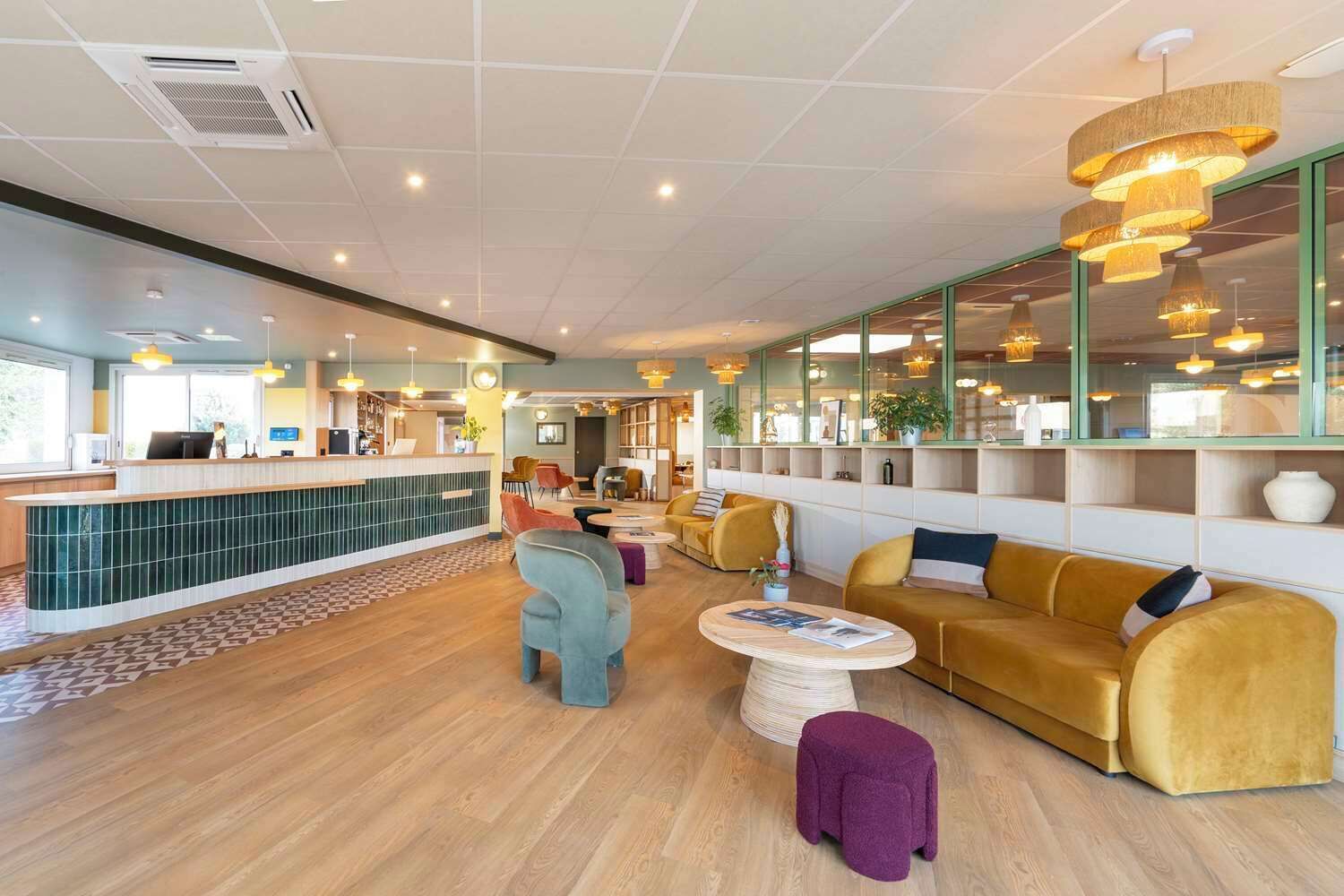 Een modern interieur met een receptiebalie, zithoek en grote ramen.