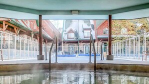 Una piscina interior con agua cristalina, rodeada de paredes de piedra y vigas de madera.
