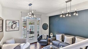 Una sala de estar moderna con un sofá gris, un sillón negro y una mesita de centro. Hay un ventanal con vistas al exterior.