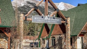 Un lodge rústico con fachada de piedra y vigas de madera, llamado 'Mystic Springs Chalets & Hot Pools'.